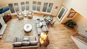 A spacious living room with a large window, a fireplace, and a dining area. - Northern Door County Waterfront Home (Sturgeon Bay)