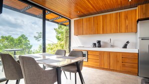 Eine moderne Küche mit Holzschränken, einem Edelstahlkühlschrank und einem Essbereich mit Tisch und Stühlen.