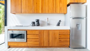 Eine moderne Küche mit Holzschränken, einem Edelstahlkühlschrank, einem Einbauofen und einer Kaffeemaschine.