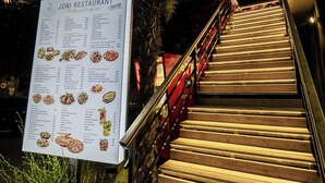 Un cartel de menú de restaurante con una escalera que lleva a la entrada.