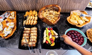 Un bufé con diversas opciones de comida, incluyendo pasteles, frutas y bocadillos.