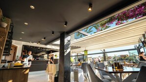 Un restaurante moderno con barra, amplios ventanales y vistas a la ciudad.