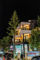 Un edificio moderno con un restaurante llamado "Hot-Dog by Joni" en la planta baja.