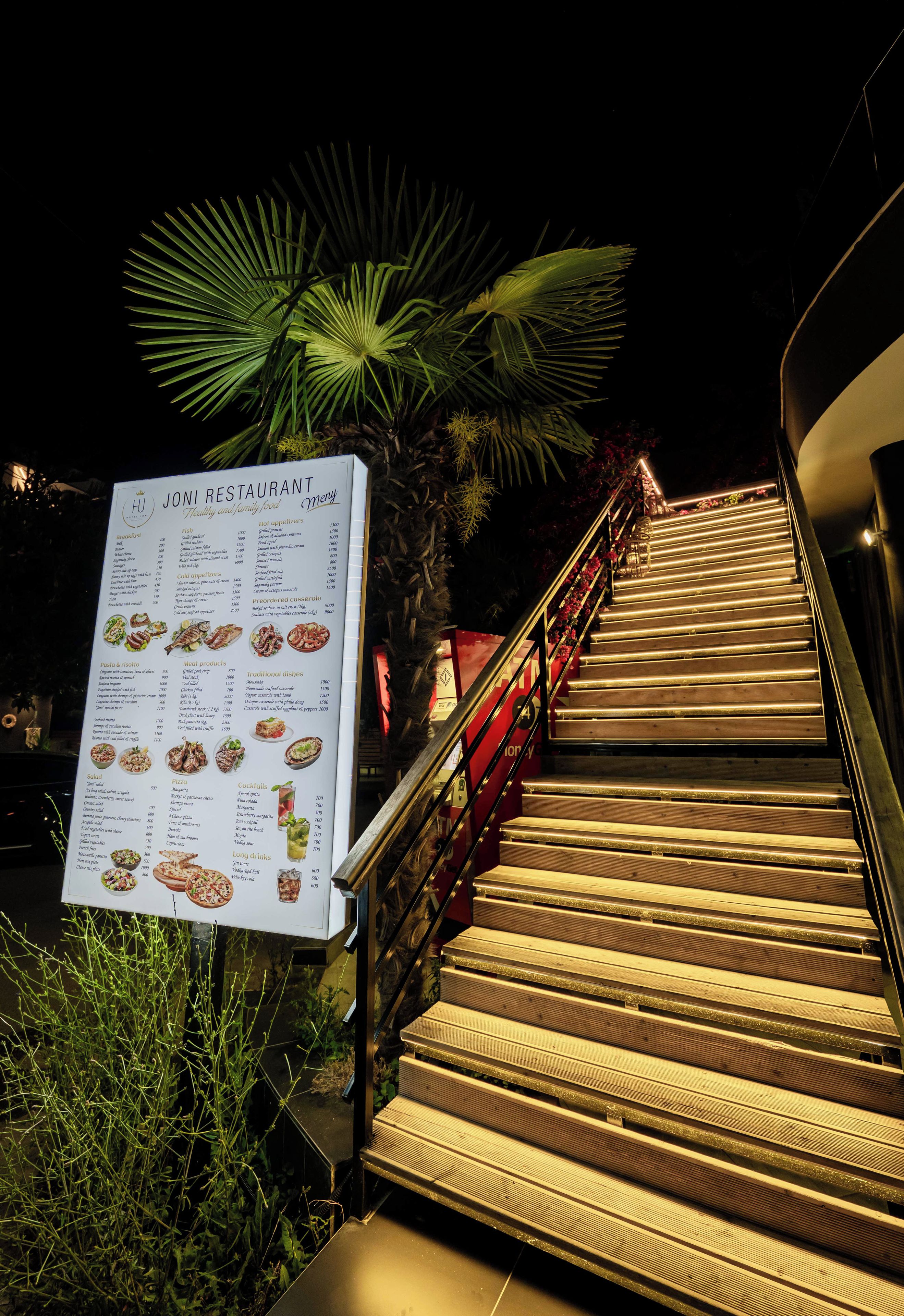 Un cartel de menú de restaurante con una escalera que lleva a la entrada.
