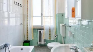 Un baño con bañera, dos lavamanos, inodoro y radiador.