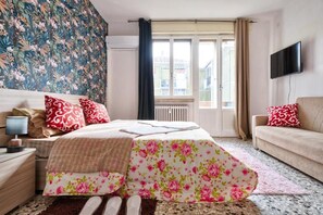 A bedroom with a bed, a sofa, a TV, and a window with curtains. - R&R APARTMENT (Mestre)