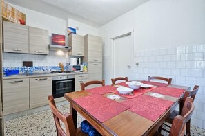 A compact kitchen with a dining table set for four, featuring a red table runner and matching placemats. - R&R APARTMENT (Mestre)