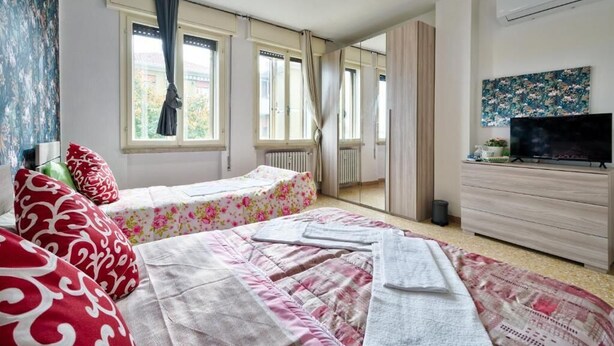 Un dormitorio con dos camas, un aparador, un televisor y una ventana con cortinas.