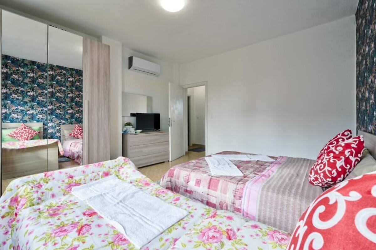 A bedroom with two beds, a dresser, a television, and a mirror.