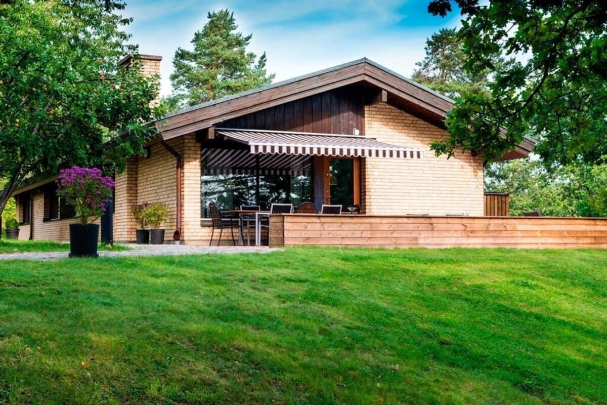 Une maison moderne dotée d’un patio couvert, d’une façade en briques et d’une pelouse bien entretenue.