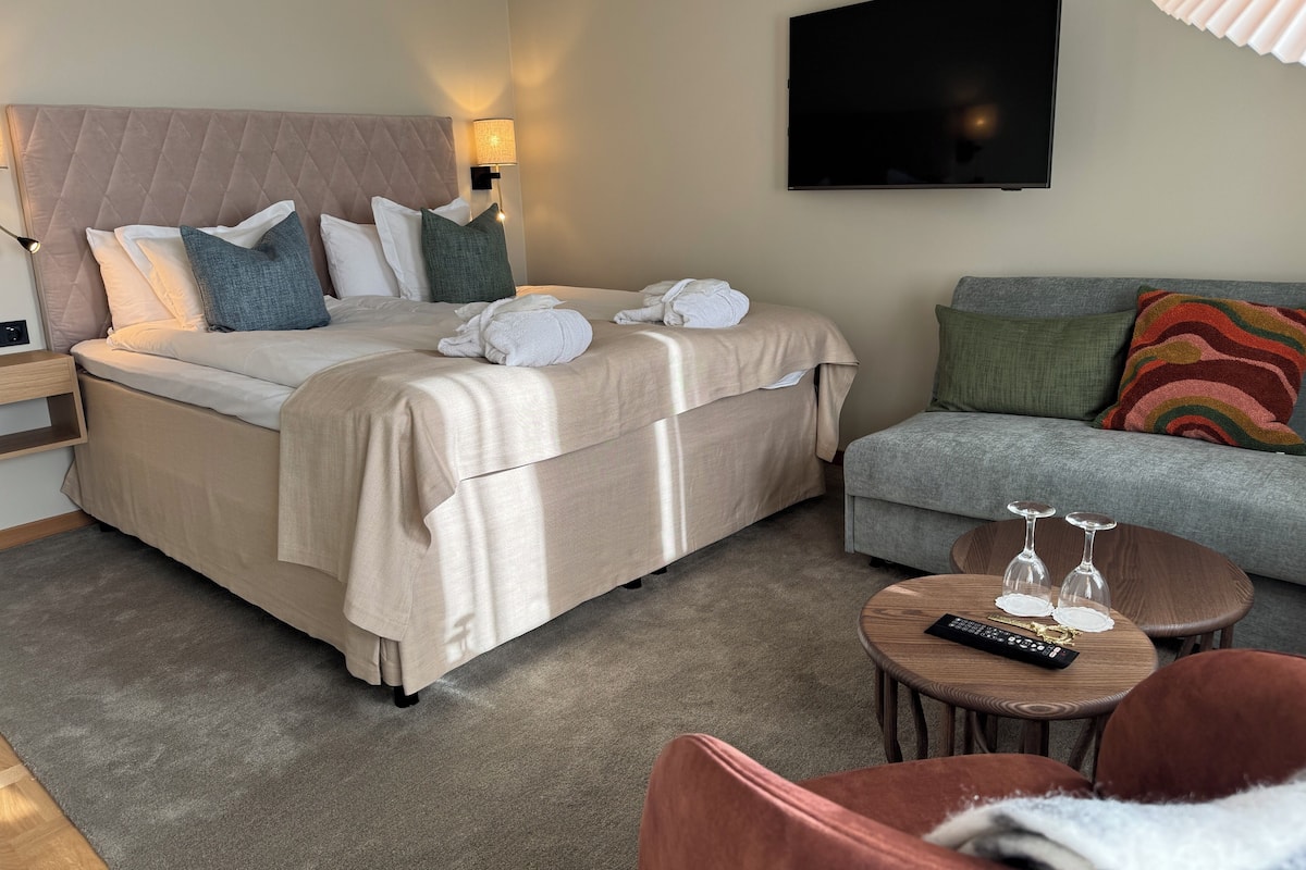 Une chambre d’hôtel avec un lit, un canapé, une télévision et une petite table avec une télécommande.