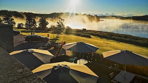 A lakeside view with a clear sky, a parked car, and outdoor umbrellas. - Skåvsjöholm hotell & konferens (Akersberga)