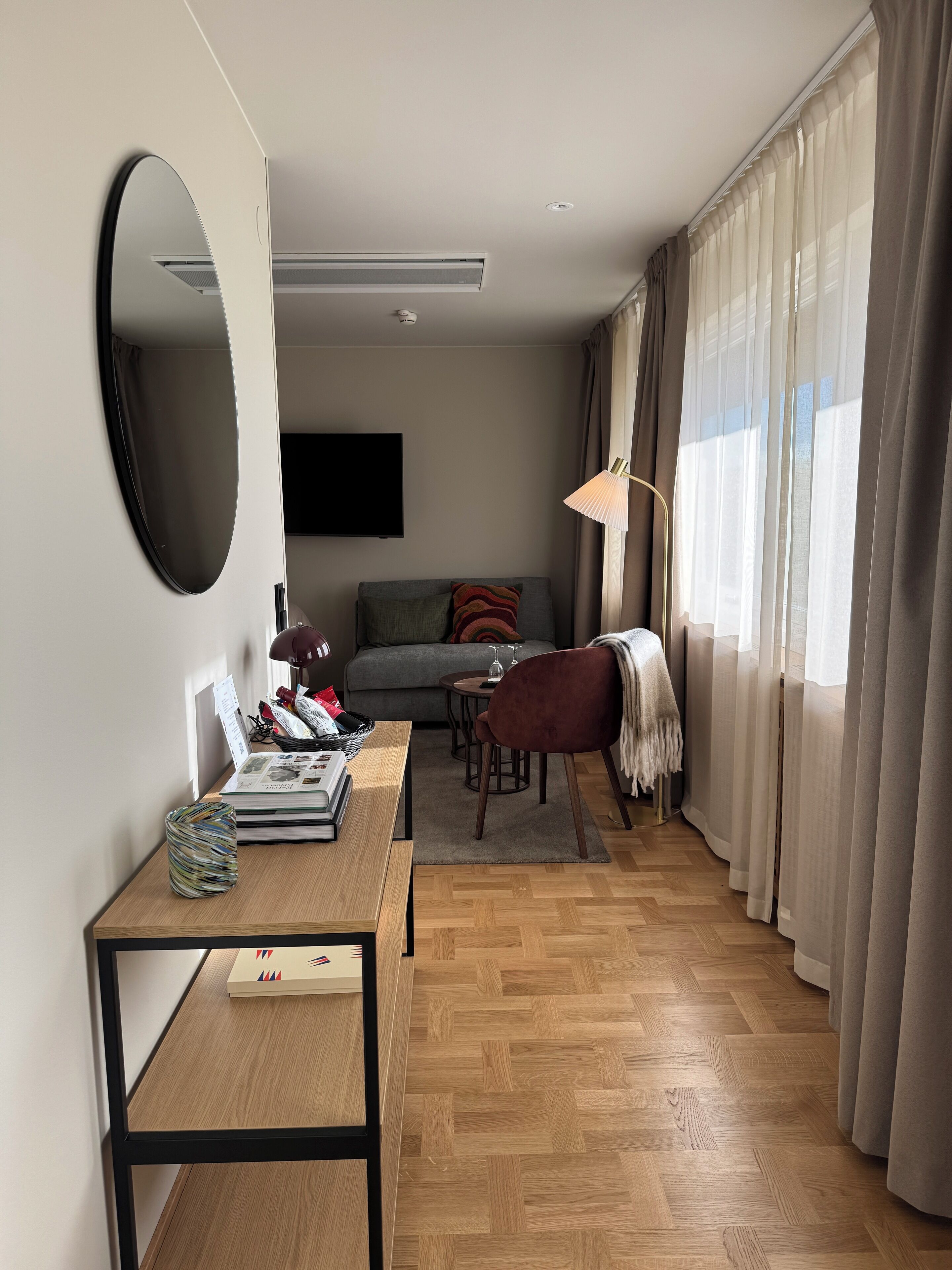 A modern living room with a sofa, a coffee table, a TV, and a dining area with a lamp.