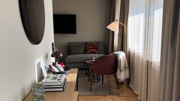 A modern living room with a sofa, a coffee table, a TV, and a dining area with a lamp.