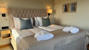 A neatly made bed with a quilted headboard, two bedside lamps, and two framed pictures on the wall. - Skåvsjöholm hotell & konferens (Akersberga)