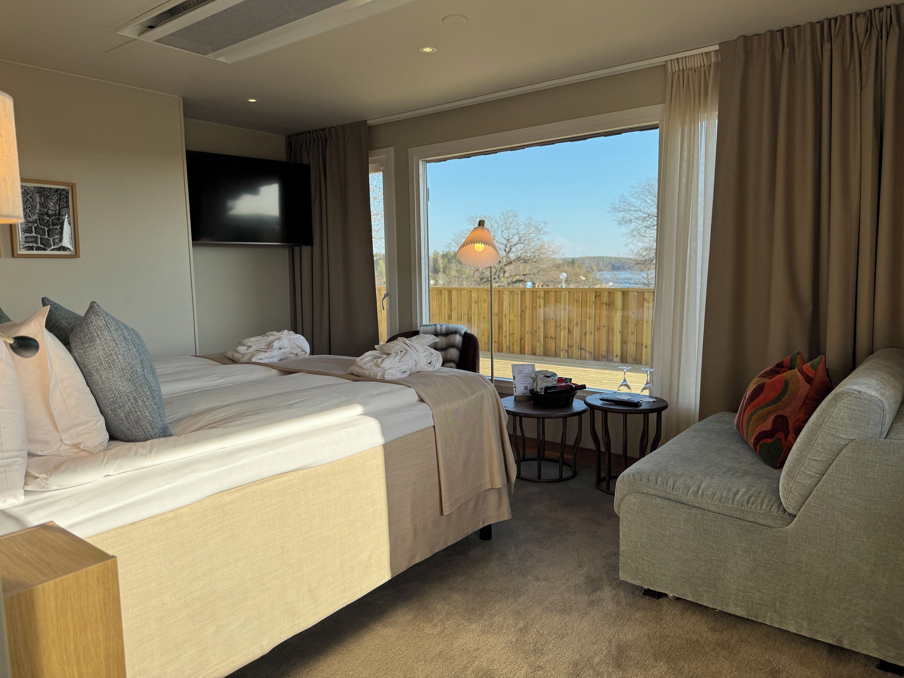 Ein Hotelzimmer mit einem Bett, einer Couch, einem kleinen Tisch und einem an der Wand befestigten Fernseher.