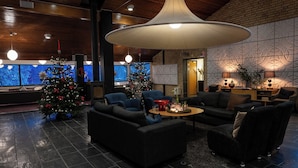 A modern lobby with dark sofas, a large central table, and two Christmas trees. - Skåvsjöholm hotell & konferens (Akersberga)
