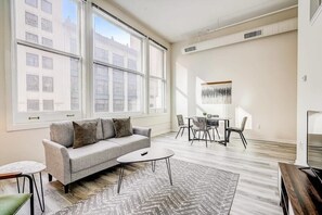 Relax in this stylish living room with a city view, featuring a sofa, coffee table, and dining area.
