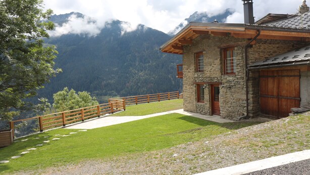 A stone house with a wooden deck and a view of mountains. - Chalet vue Imprenable (Montvalezan)
