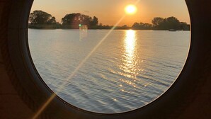 A circular window with a sunset view over a body of water. - Time out on the Havel - Houseboat "nautikhus" (Werder (Havel))
