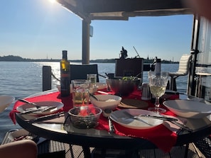 Ett dukat bord för en måltid med utsikt över vattnet, en flaska och olika rätter.
