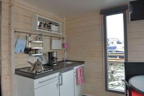 Ett kompakt kök med vattenkokare, kaffebryggare och utsikt över vattnet.