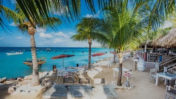 Ranta lähistöllä, aurinkotuoleja, rantapyyhkeitä