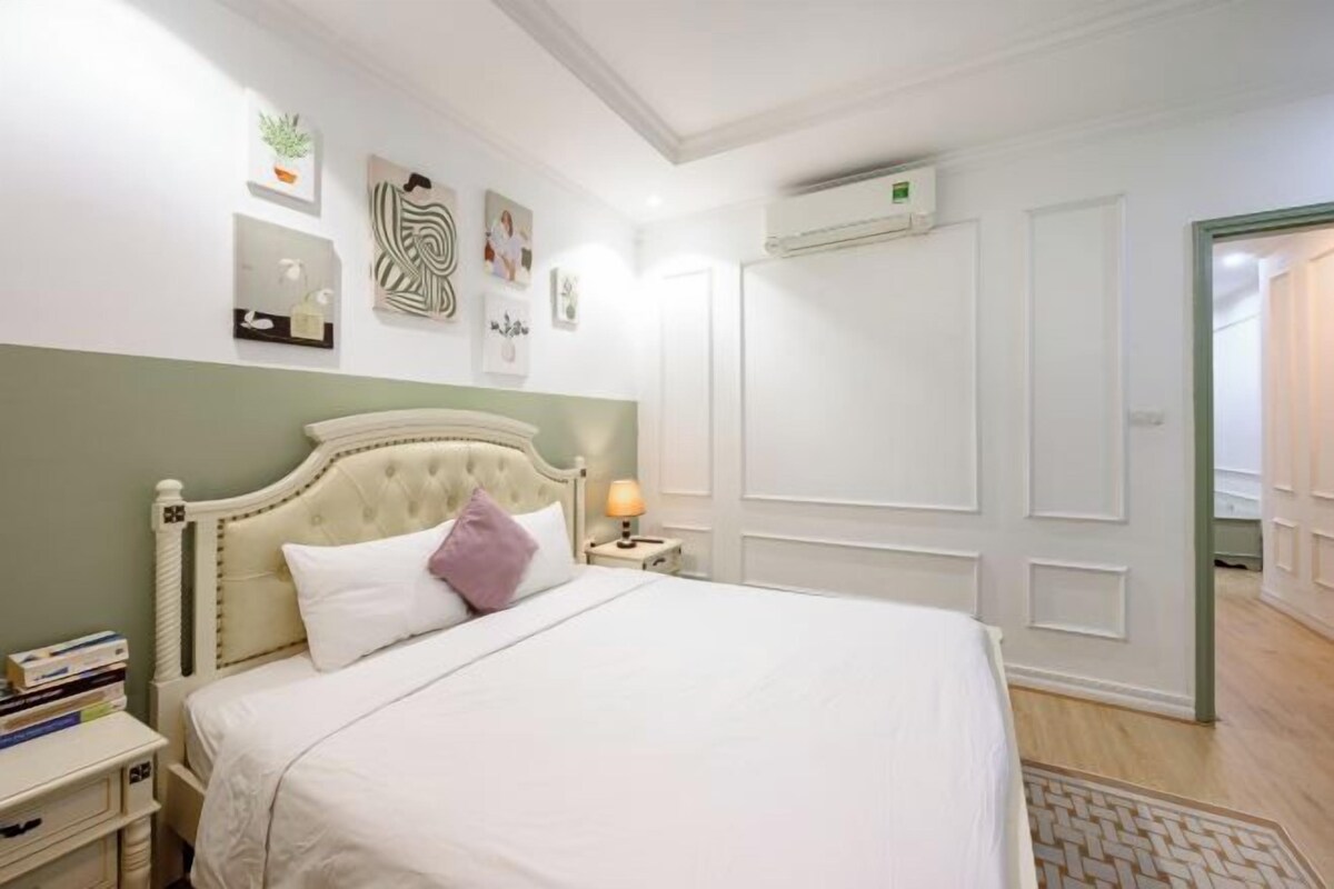 A neatly arranged bedroom with a bed, bedside table, and wall art.