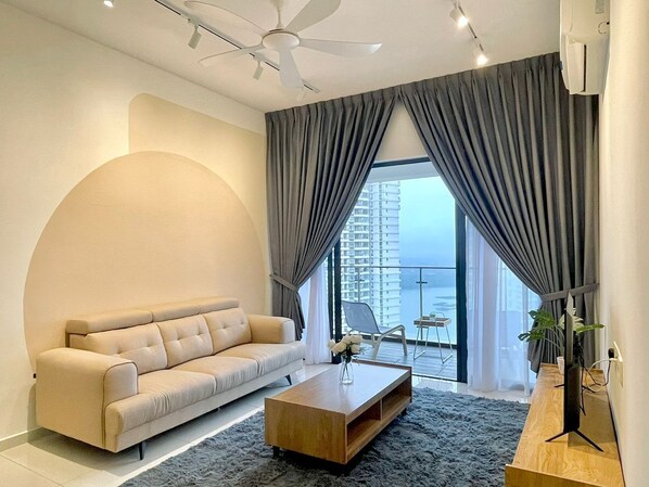 A modern living room with a sofa, coffee table, and a view of the city through large windows. - Country Garden By Antlerzone (Johor Bahru)