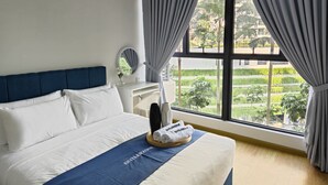 Habitación de hotel con una cama, mesita de noche, espejo y ventana con cortinas.