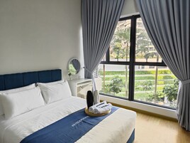 A hotel room with a bed, a bedside table, a mirror, and a window with curtains.