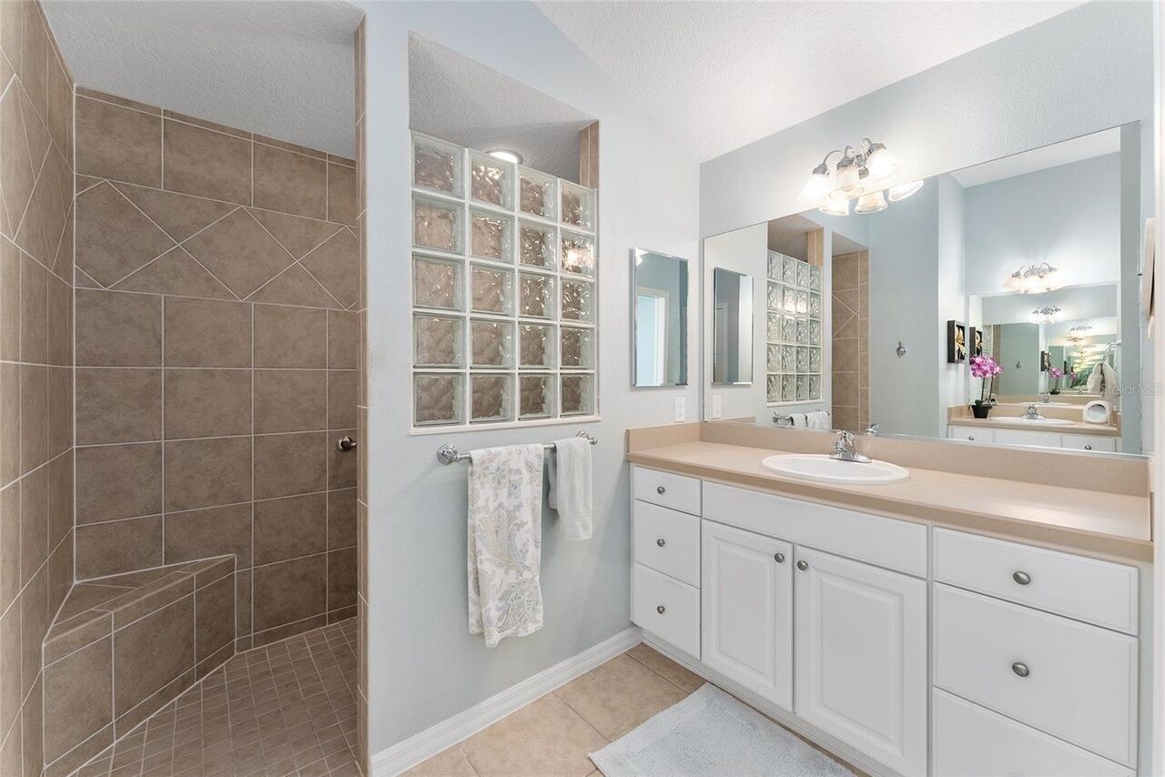 A modern bathroom with a walk-in shower, a large mirror, and a vanity with a sink.