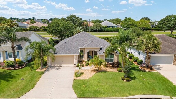 A residential neighborhood with single-family homes, well-maintained lawns, and palm trees.