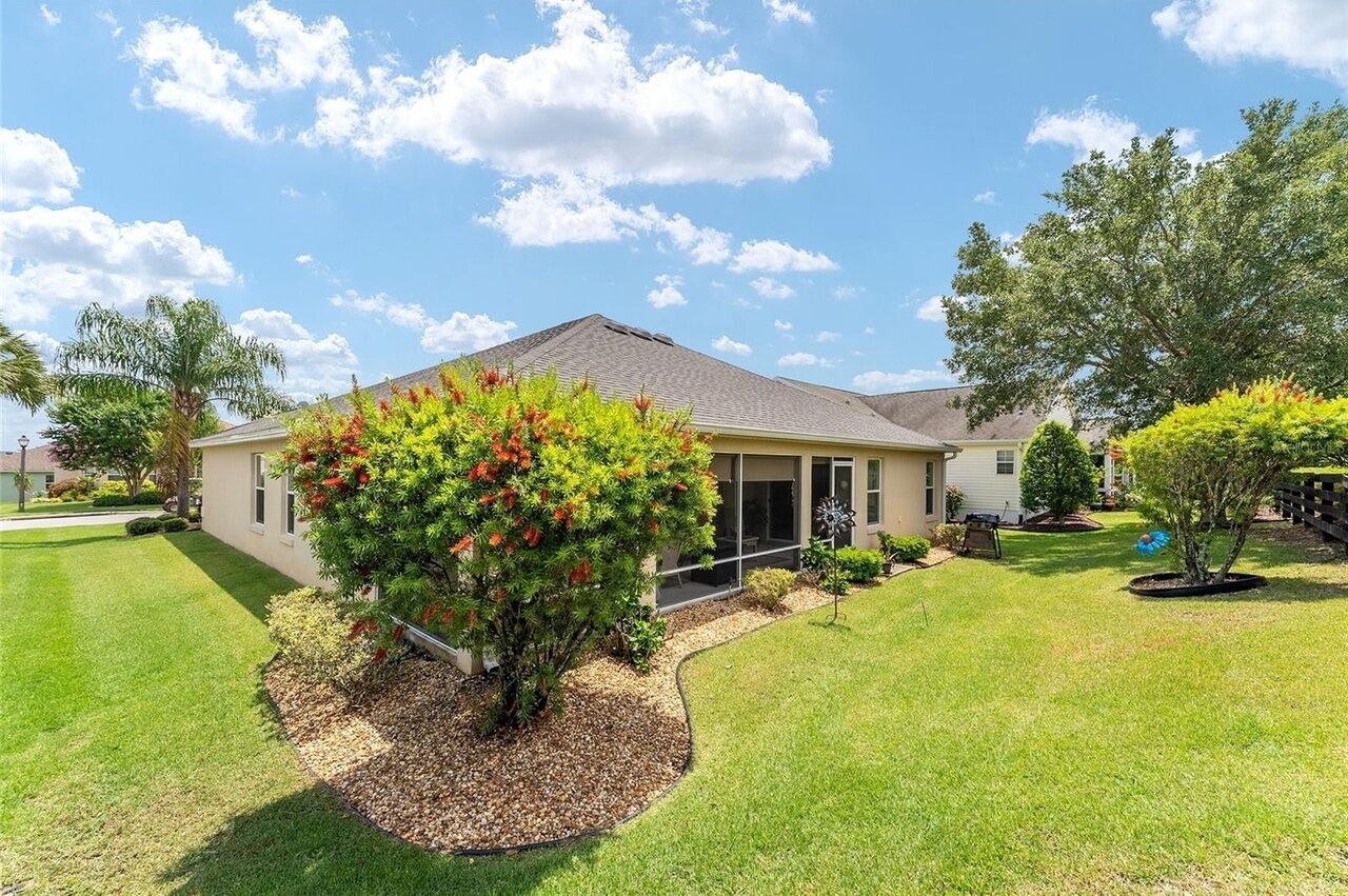 A single-story house with a well-maintained lawn and a large tree in the front yard.