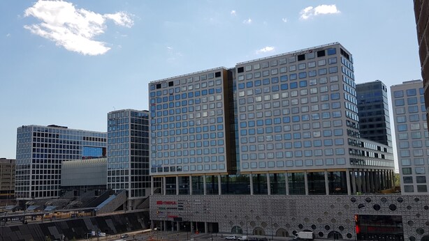 Un hôtel moderne doté d’une façade en verre, de plusieurs étages et d’une entrée imposante.