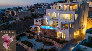Una villa moderna con piscina, varios balcones y fachada de piedra.