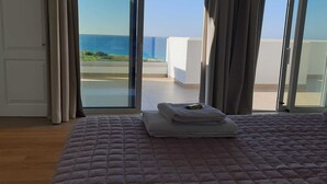 Un dormitorio con cama, vistas al mar y un balcón con barandilla.