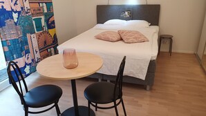 A hotel room with a bed, two chairs, a small round table with a glass, and a colorful wall mural. - Cozy corner next to the Mall of Tripla (Helsinki)