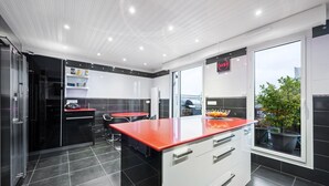 Una cocina moderna con armarios blancos y negros, una encimera roja y un reloj digital.