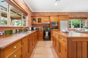 A kitchen with wooden cabinets, a stainless steel sink, a microwave, and a refrigerator. - 6 Minutes from Bathurst CBD - The Estait Homestead - Laffing Waters Retreat (Laffing Waters)