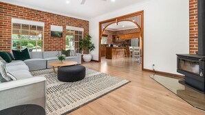 A modern living room with a brick wall, a sofa, a coffee table, and a fireplace. - 6 Minutes from Bathurst CBD - The Estait Homestead - Laffing Waters Retreat (Laffing Waters)