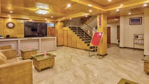 A lobby with a reception desk, a staircase, and a reception area. - Hotel Grand Oasis (Manali)