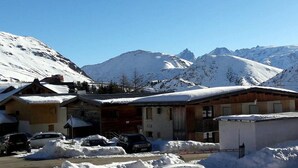 A snow-covered mountain town with wooden buildings and parked cars.