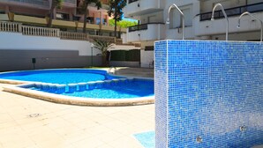 Une piscine avec un bord carrelé et une petite cascade décorative.