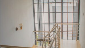 Una escalera con barandillas metálicas y vista a un edificio a través de amplias ventanas.