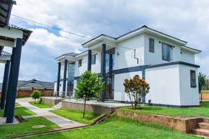 A modern two-story building with a flat roof, large windows, and a concrete pathway leading to the entrance.