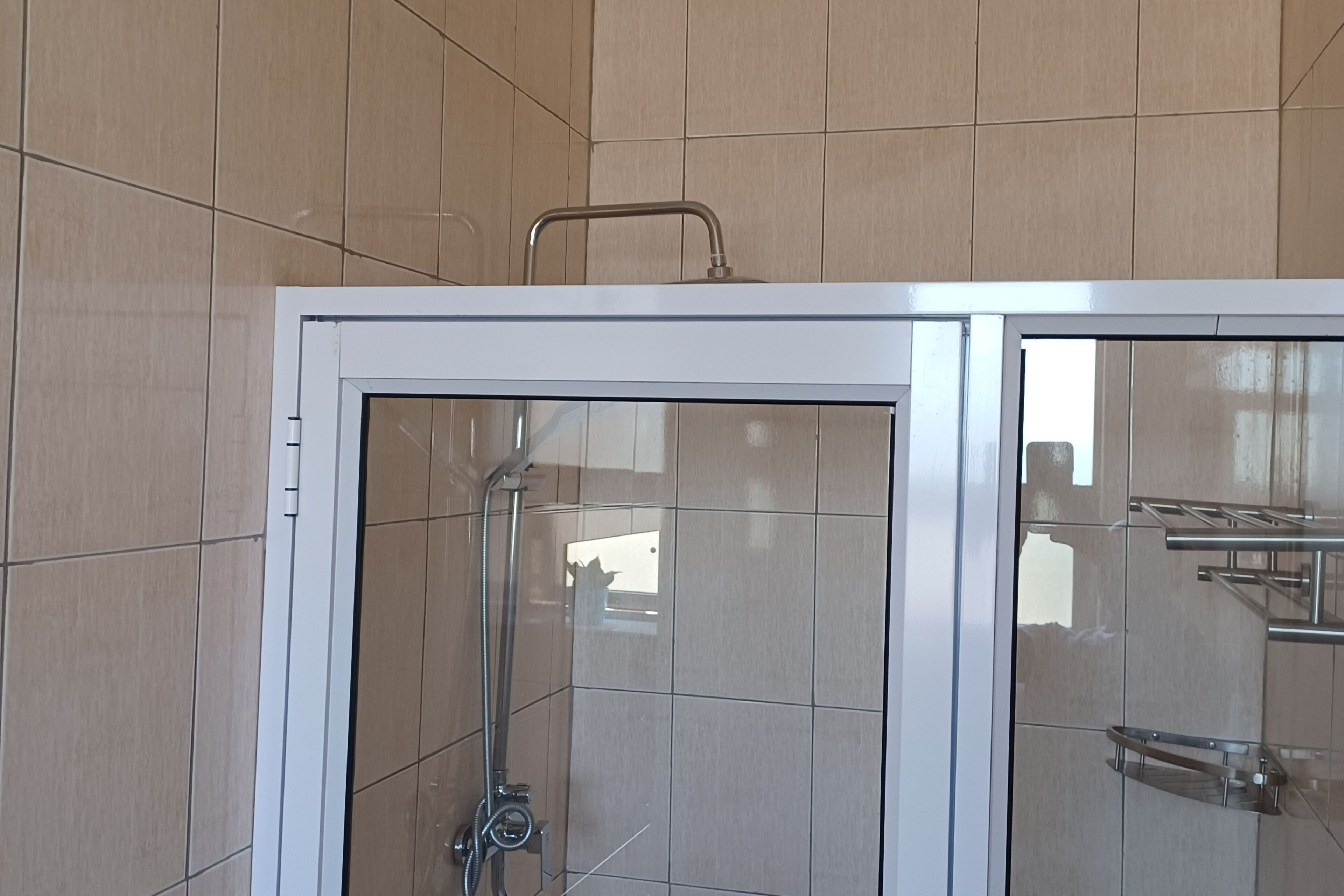 A shower enclosure with a glass door and a metal handle.