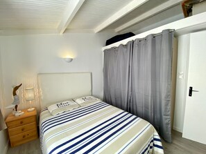 Ein Schlafzimmer mit einem Bett, einem Nachttisch, einer Wandleuchte und einer Tür.