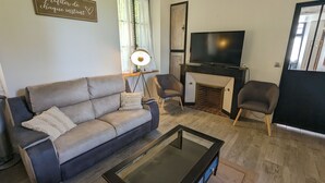 A living room with a sofa, armchairs, a coffee table, a fireplace, and a TV.