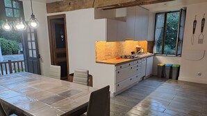 A modern kitchen with a wooden countertop, white cabinets, and a dining area with a large table and chairs.